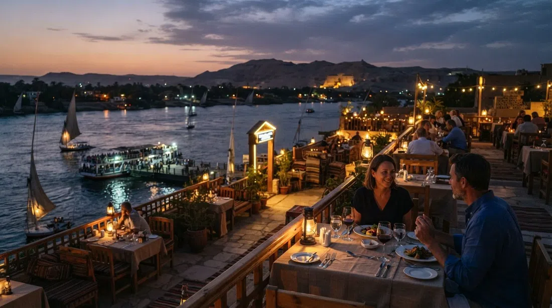 la azotea de Sunflower Restaurant junto al muelle del ferry al atardecer, con el Nilo abajo, mesas preparadas para cenar y el cielo de la orilla oeste desvaneciéndose sobre el río